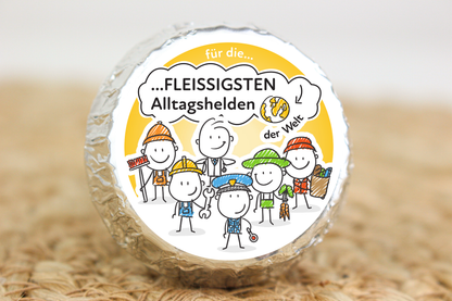 Silber verpackter Schokotaler mit verschiedenen Berufsfiguren und Aufschrift „Für die fleißigsten Alltagshelden der Welt“