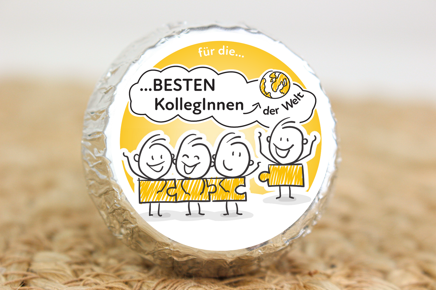 Silber verpackter Schokotaler mit Strichmännchen-Team und Aufschrift „Für die besten KollegInnen der Welt“