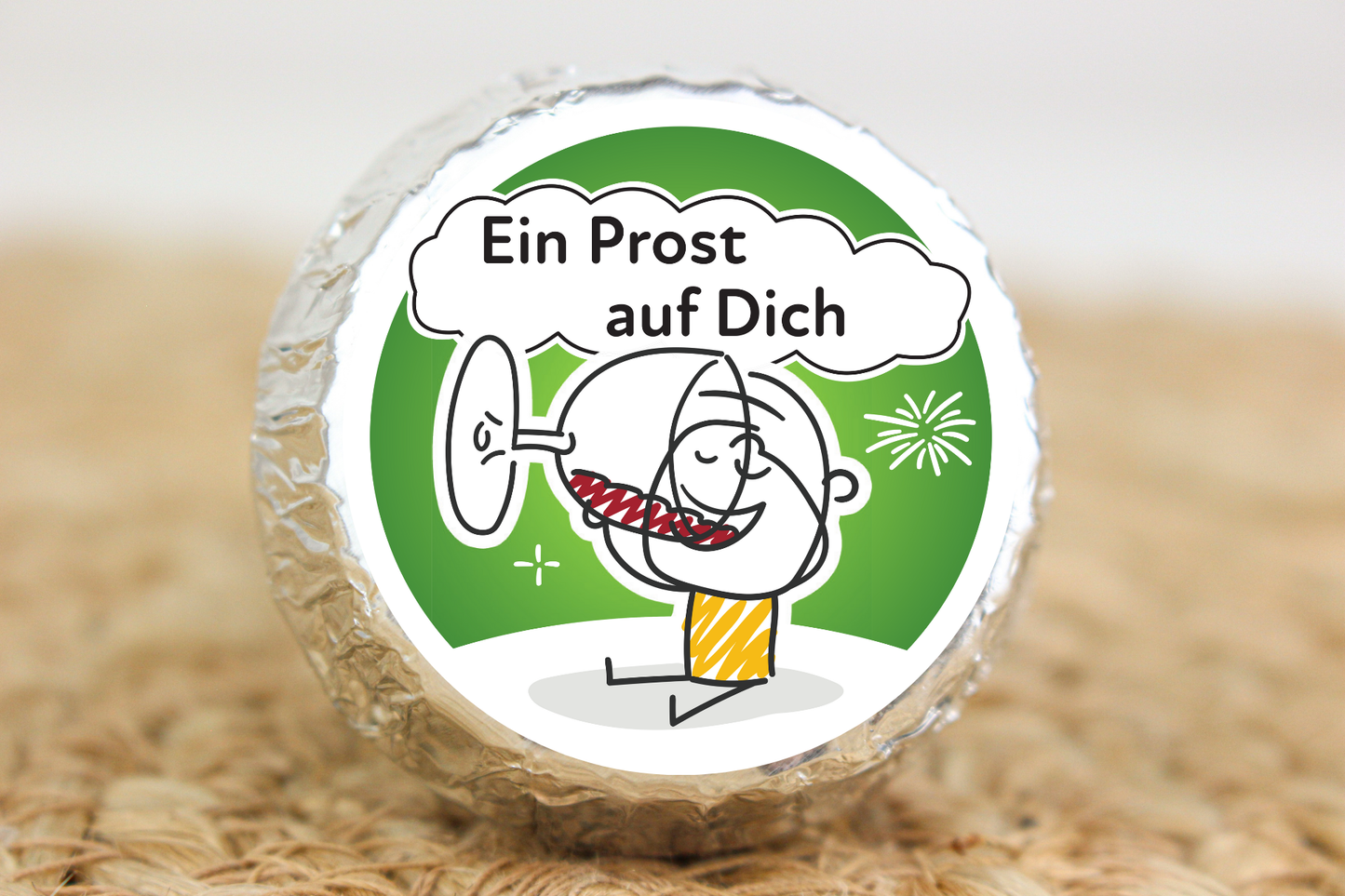 Silber verpackter Schokotaler mit anstoßendem Strichmännchen und Aufschrift „Ein Prost auf Dich“