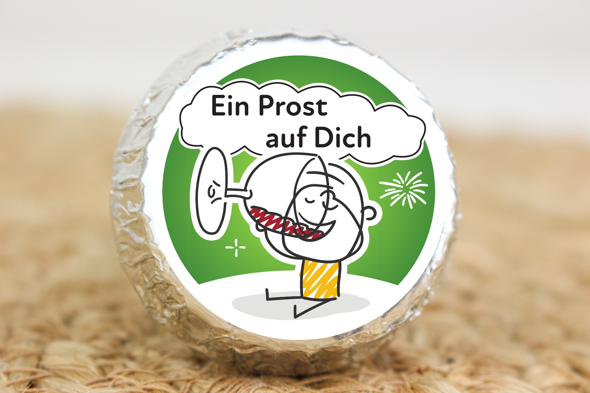 Silber verpackter Schokotaler mit anstoßendem Strichmännchen und Aufschrift „Ein Prost auf Dich“