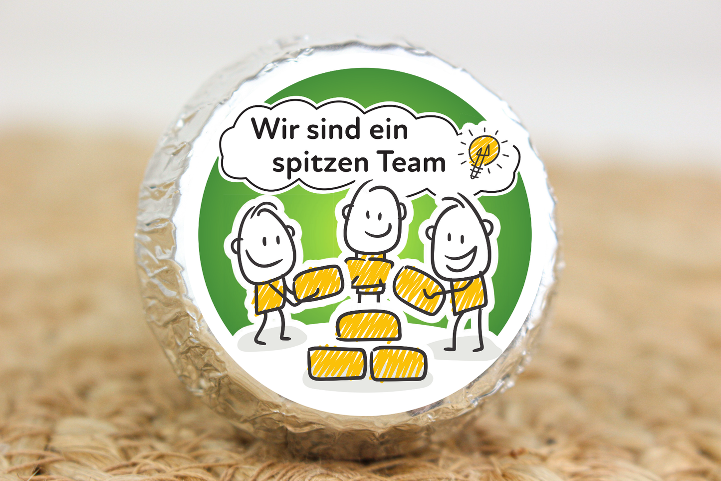 Silber verpackter Schokotaler mit Strichmännchen-Team und Aufschrift „Wir sind ein spitzen Team“