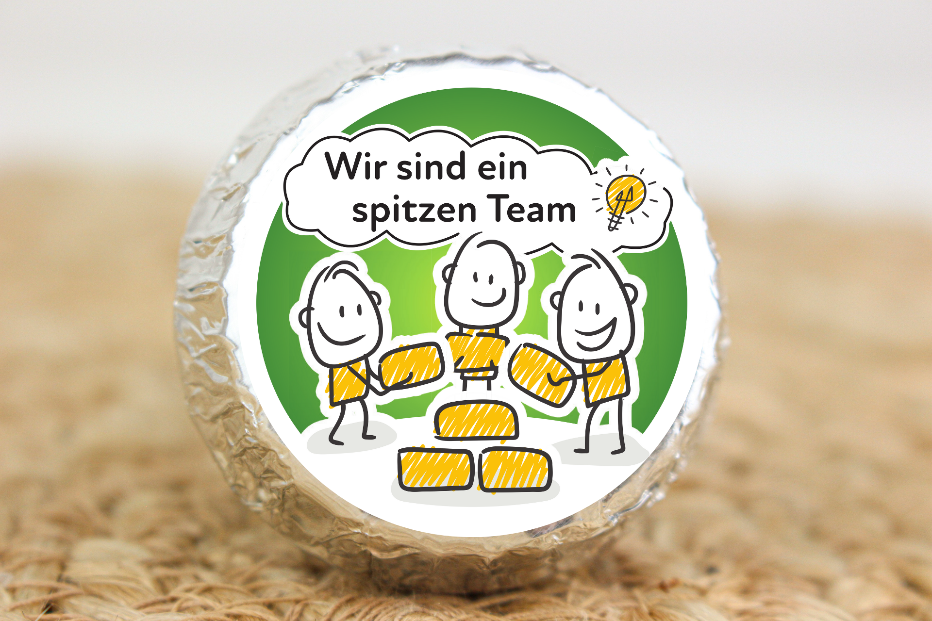 Silber verpackter Schokotaler mit Strichmännchen-Team und Aufschrift „Wir sind ein spitzen Team“
